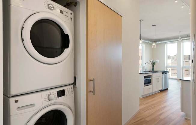 A white washing machine and dryer stacked on top of each other in a kitchen.