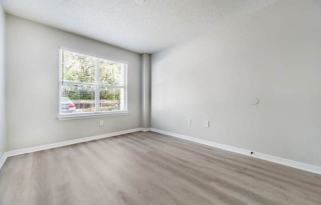 A room with a window and a wooden floor.