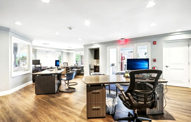 a conference room with desks and chairs on a wood floor