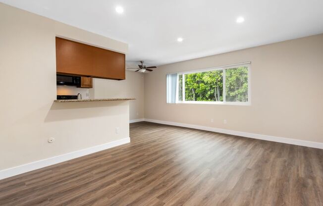 an empty living room with a large window and hardwood floors