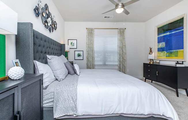 A bedroom with a large bed and a ceiling fan.