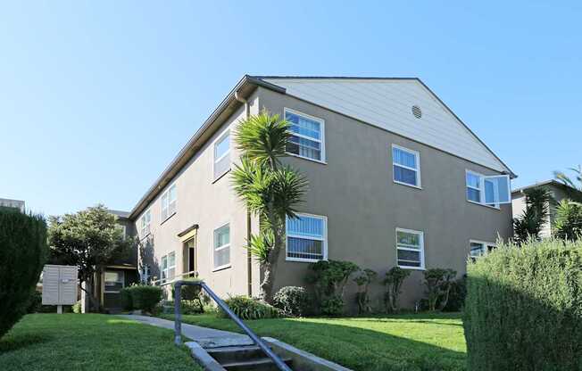 A house with a grey roof and a green lawn in front.