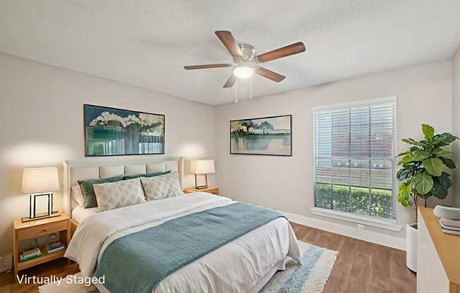 A bedroom with a bed, two lamps, a ceiling fan, and two pictures on the wall.