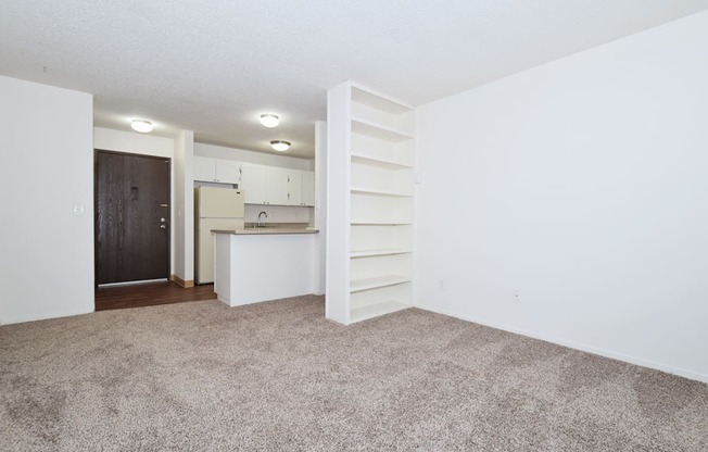 a spacious living room with a kitchen in the background