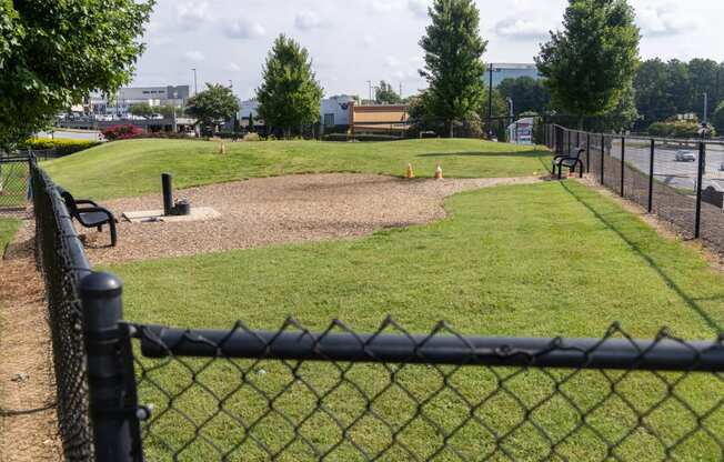 a park with a dirt field and a fence