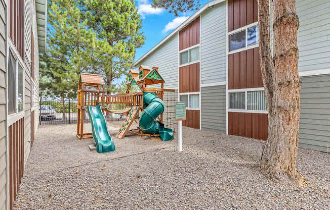 A playground area with a green slide and a wooden structure t Wildflower Apartments in Kennewick, WA..