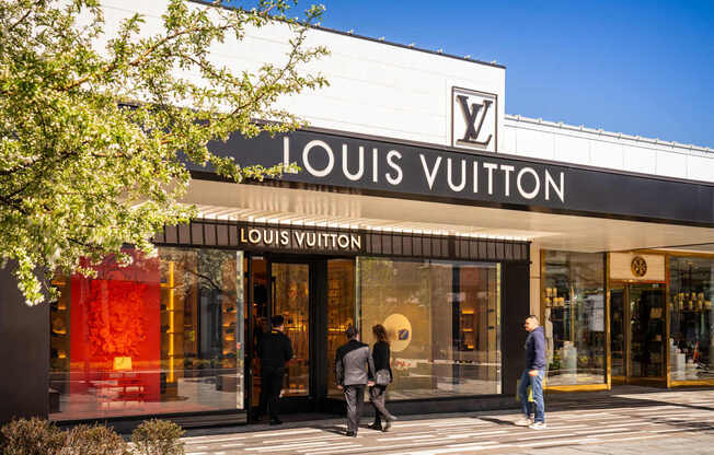 A Louis Vuitton store with people walking in front.