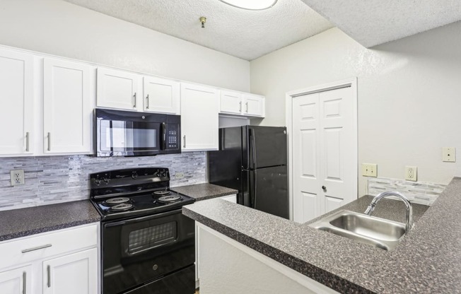 A1 floor plan kitchen with black appliances and elevated counter at Jefferson Creek Apartments in Irving, TX.