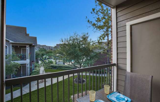 a balcony with a table and chairs overlooking a yard and houses