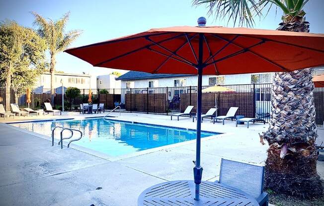 a pool with a table and umbrella next to it at Fiesta Apts, Lompoc, CA