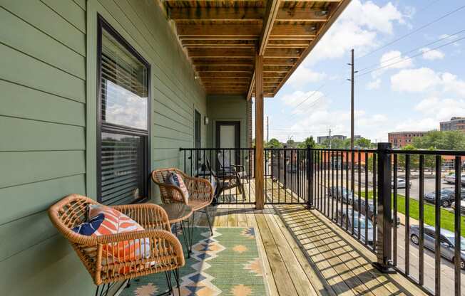 a balcony with wicker chairs and a view of the indianapolis at the vue apartments