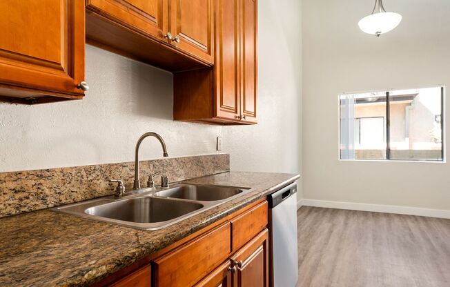 A kitchen with a granite countertop and wooden cabinets.