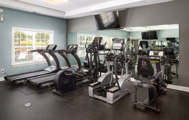 a room filled with lots of cardio equipment and a flat screen tv