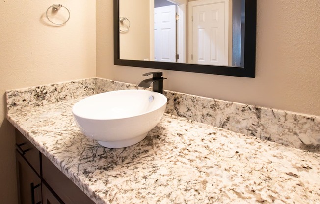 A white sink is on a marble countertop.