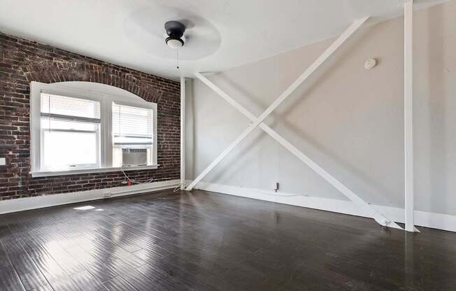 An apartment living room with a brick wall and wooden flooring at Brookmore Apartments in Pasadena, CA.