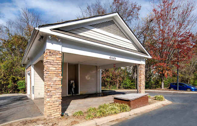 A small white building with a gabled roof and a brick pillar.