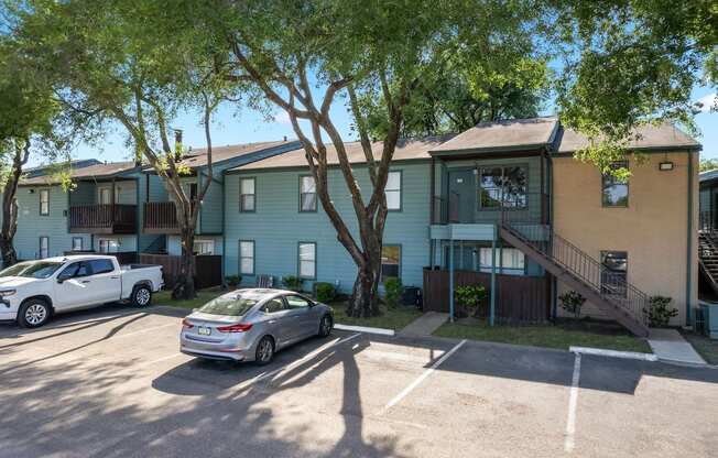 an apartment building with cars parked in a parking lot