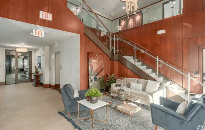A living room with a staircase and exit signs.