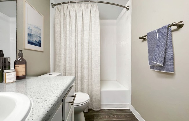 A bathroom with a white shower curtain and a blue towel hanging on the towel rack.