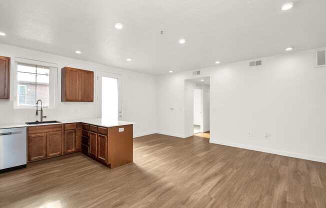 an empty kitchen and living room with wood floors and white walls