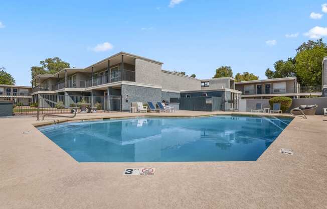 a swimming pool in front of a house with a building in the background