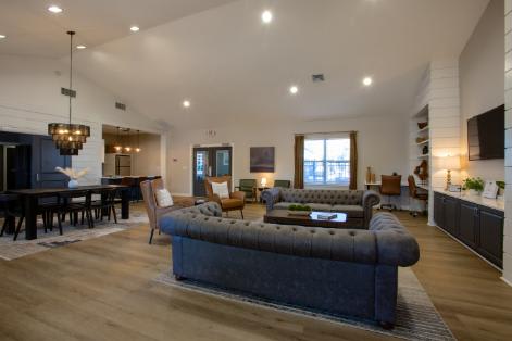 A modern living room with a large grey sofa and wooden floors.