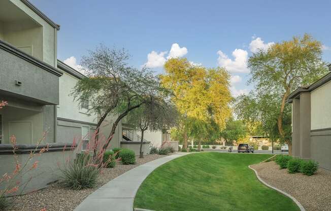 a walkway between two apartment buildings with grass and trees