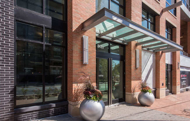 A modern building with a glass entrance and two large planters in front.