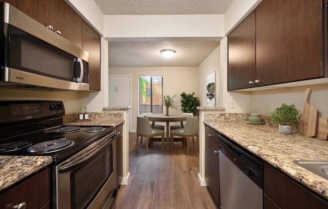 view of kitchen and dining room with stainless steel appliances and granite counter tops