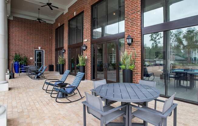 a patio with a table and chairs outside of a brick building at Volare at the Woodlands, The Woodlands, Texas