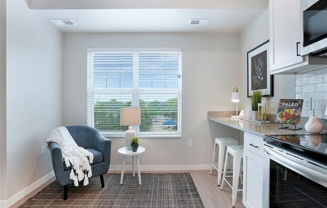 A kitchen with a grey chair and a table with a white cloth on it.