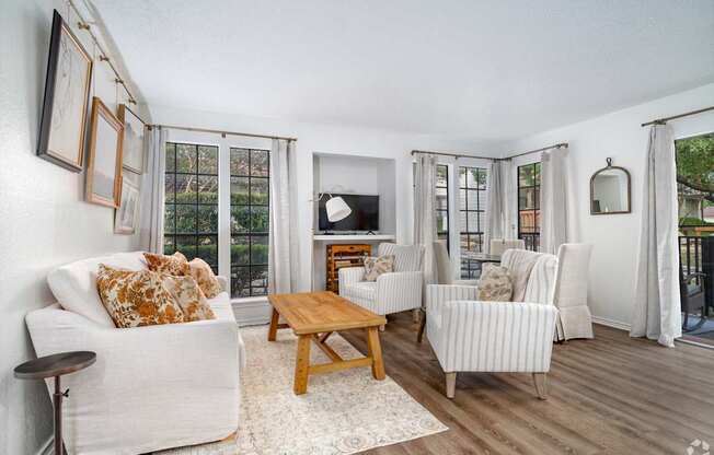 A living room with a white couch, a wooden coffee table, and a television.