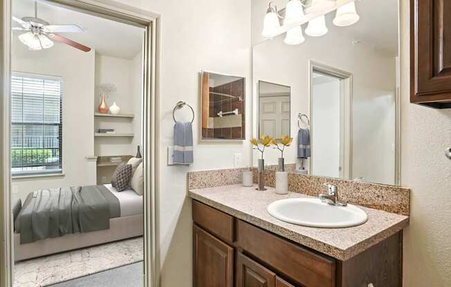 A bathroom with a large mirror, a bed, and a sink.