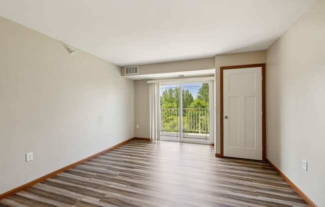 an empty living room with a door to a balcony