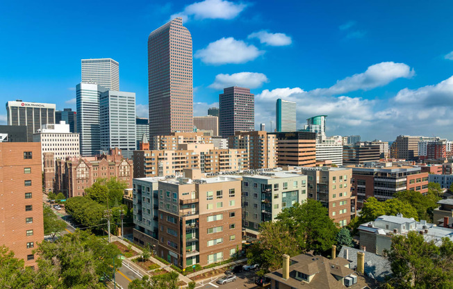 Denver skyline showing the apartment building on a sunny day with blue sky and white clouds at Sylvan Uptown, Denver, CO