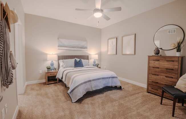 A bedroom with a bed, nightstand, and dresser and ceiling fan with light.