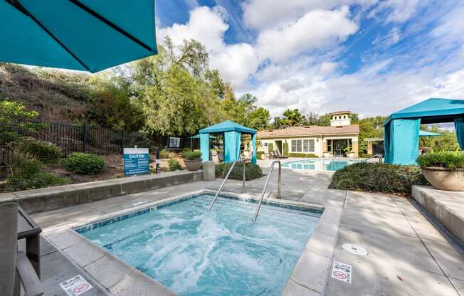 a swimming pool with two blue umbrellas and a house in the background