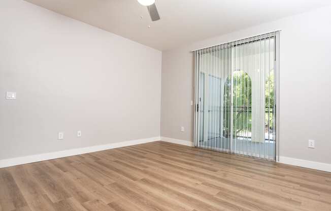an empty living room with a sliding glass door to a patio