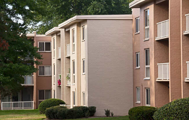 Apartment building with balconies and bushes in front.