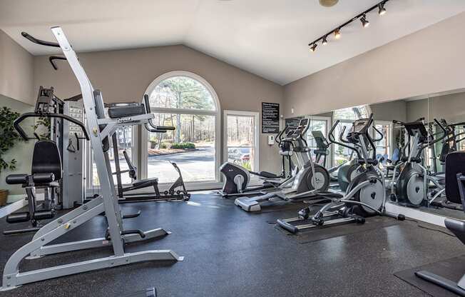 a gym with cardio machines and other exercise equipment and a window