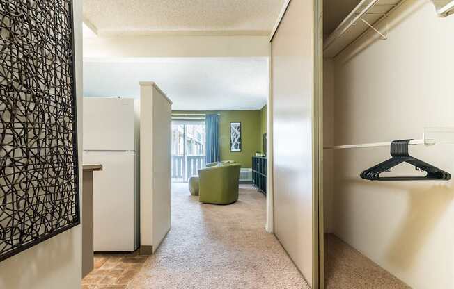 A hallway with a white fridge and a green chair.