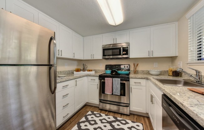 Kitchen with Granite Counters, Dishwasher, Oven, Microwave, Black/White Rug and White Cabinents