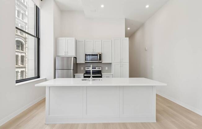 A kitchen with white cabinets and a white island.