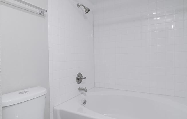 a white bathroom with a toilet and a tub