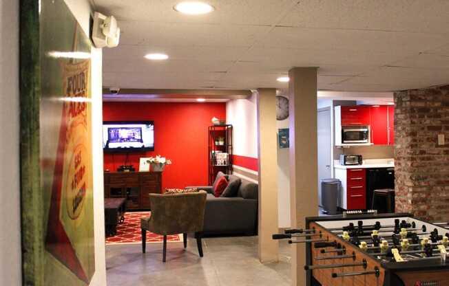 Brookmore apartments rec area with foosball table; kitchen area with toaster, microwave, and red cabinets; and living room with TV and couches.