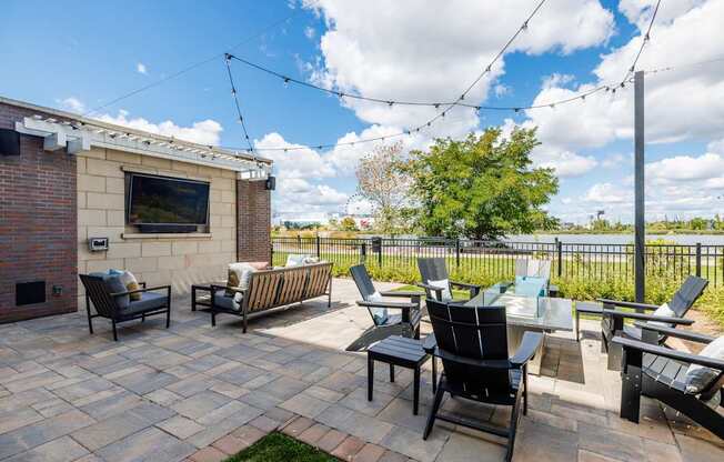 A patio with black chairs and a television on a brick wall.