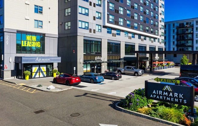A red car is parked in front of a building with a sign that says