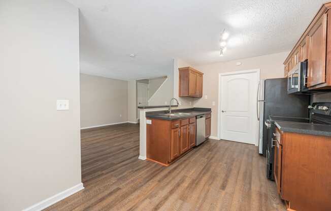 an empty kitchen with wood flooring and black appliances