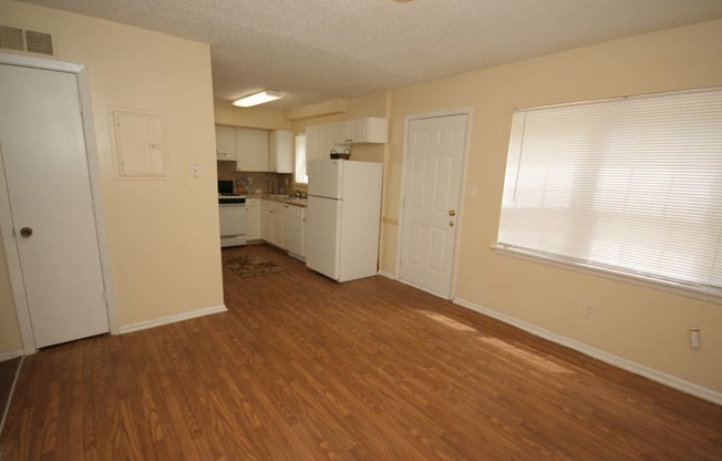 an empty kitchen and living room with wood flooring and white appliances