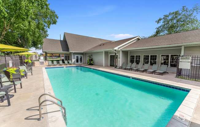 A pool with a metal railing and a house in the background.